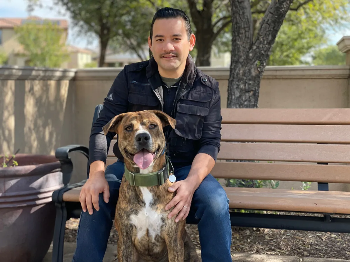 Robert Velazquez with a brindle dog on a park bench